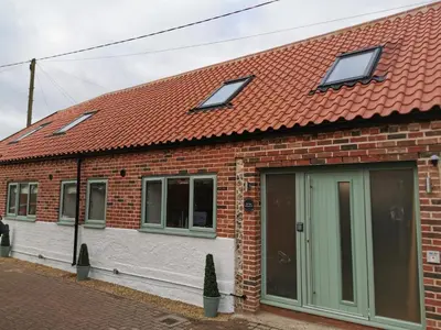 a brick house with a red roof and windows at The Barn in Swaffham
