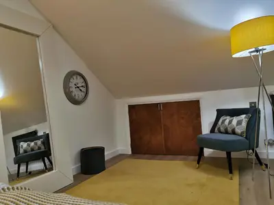 a bedroom with a door and a chair and a clock at The Barn in Swaffham