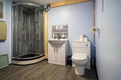 a bathroom with a shower and a toilet and a sink at Hatters Meadows Glamping in Ely