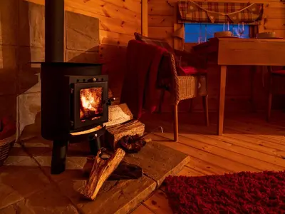 a woodburning stove in a room with a table at Hatters Meadows Glamping in Ely