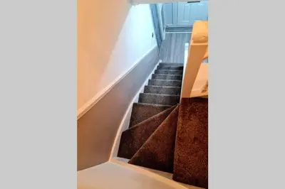 a staircase with brown carpeted stairs with a wooden railing at Berrygate in Ipswich