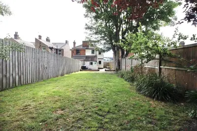 a backyard with a wooden fence and a grass yard at Berrygate in Ipswich