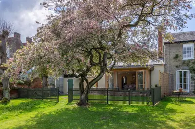 a tree in front of a house with a fence at Gothic House Cottage in Clare