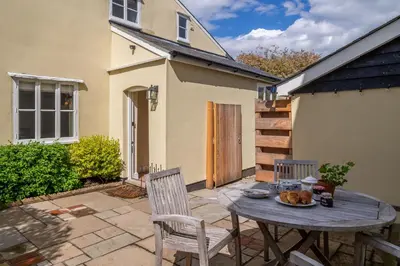 a patio with a table and chairs and a house at Gothic House Cottage in Clare