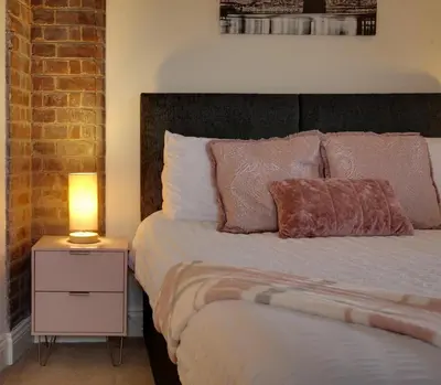 a bedroom with a bed with a lamp on a night stand at Niche Water Tower Apartments in Braintree