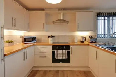 a kitchen with white cabinets and a stove top oven at Niche Water Tower Apartments in Braintree
