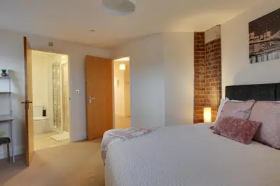 a bedroom with a bed and a brick wall at Niche Water Tower Apartments in Braintree