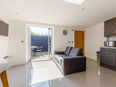 a living room with a couch and a kitchen at Blackberry Cottage in Stowmarket