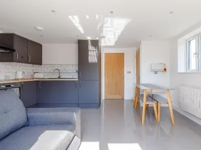 a kitchen with a couch and a table in a room at Blackberry Cottage in Stowmarket