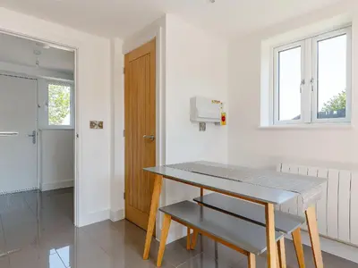 a white kitchen with a table and a window at Blackberry Cottage in Stowmarket