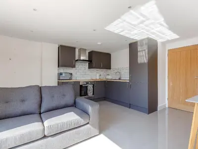 a living room with a couch and a kitchen at Blackberry Cottage in Stowmarket