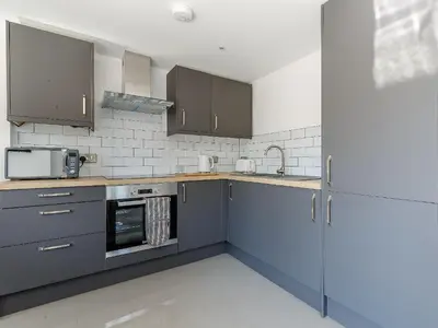 a kitchen with blue cabinets and a microwave at Blackberry Cottage in Stowmarket