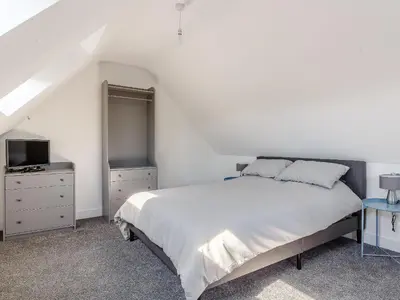 a white bedroom with a bed and a tv at Blackberry Cottage in Stowmarket