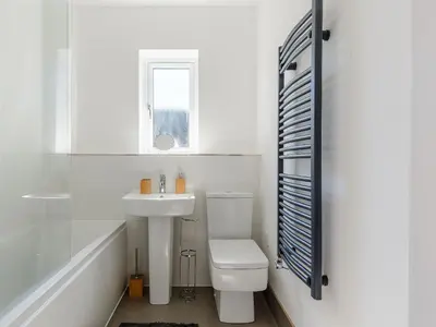 a white bathroom with a toilet and a sink at Blackberry Cottage in Stowmarket