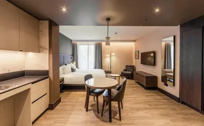 a hotel room with a bed and a table and chairs at The Fellows House Cambridge, Curio Collection By Hilton in Cambridge