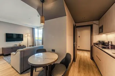 a living room with a table and chairs and a kitchen at The Fellows House Cambridge, Curio Collection By Hilton in Cambridge