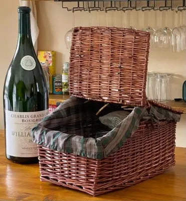 a bottle of wine in a basket next to a wine bottle at Walnut Tree Cottage Barn in Toppesfield