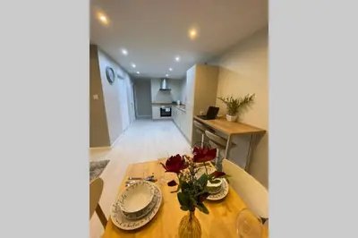 a dining room with a table and a kitchen at Modern and spacious open plan bungalow in Felixstowe