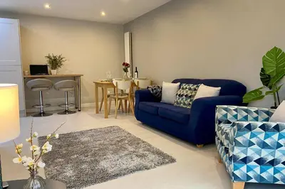 a living room with a blue couch and a table at Modern and spacious open plan bungalow in Felixstowe