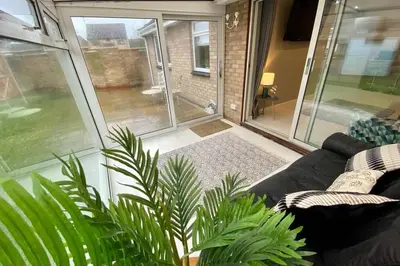 a screened in living room with a couch and a patio at Modern and spacious open plan bungalow in Felixstowe
