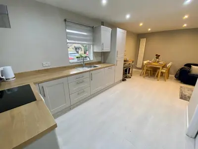a kitchen with white cabinets and a dining room at Modern and spacious open plan bungalow in Felixstowe