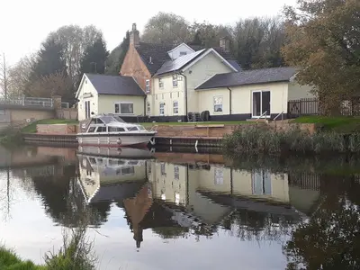 a boat is docked on a river with houses at Cottage - Sleeps 3 Parking & Fishing in Hilgay