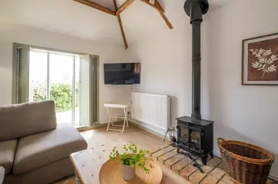 a living room with a couch and a wood stove at East Green Farm Cottages - The Old Stables in Saxmundham