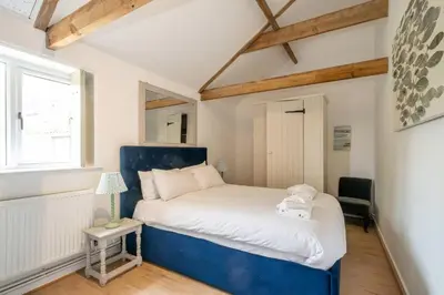 a bedroom with a blue bed and a window at East Green Farm Cottages - The Old Stables in Saxmundham