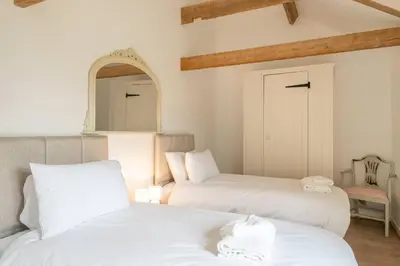 two beds in a room with a mirror and a chair at East Green Farm Cottages - The Old Stables in Saxmundham
