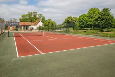 a tennis court in front of a house at East Green Farm Cottages - The Old Stables in Saxmundham