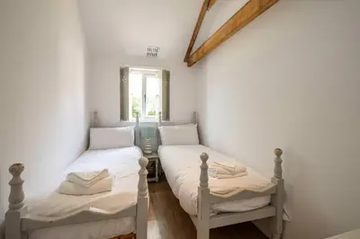 two twin beds in a room with a window at East Green Farm Cottages - The Old Stables in Saxmundham