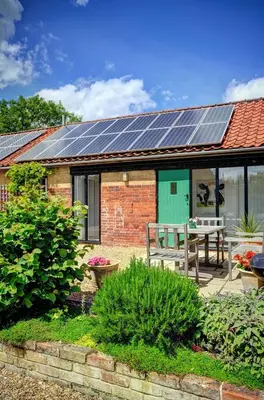 a house with solar panels on the roof at East Green Farm Cottages - The Granary in Saxmundham