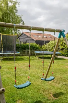 two swings in a playground with a picnic table at East Green Farm Cottages - The Granary in Saxmundham