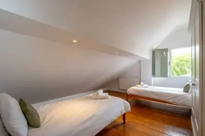 a white room with two beds and a window at East Green Farm Cottages - The Dairy in Saxmundham