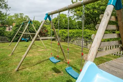 a group of swings in a yard at East Green Farm Cottages - The Dairy in Saxmundham