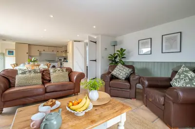 a living room with leather couches and a table with bananas at East Green Farm Cottages - The Dairy in Saxmundham