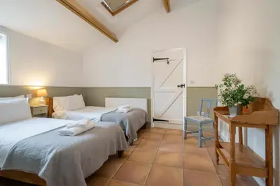 a bedroom with two beds and a table and a door at East Green Farm Cottages - Gardeners Cottage in Saxmundham
