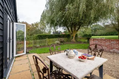 a table with chairs and a tea pot on it at East Green Farm Cottages - Gardeners Cottage in Saxmundham