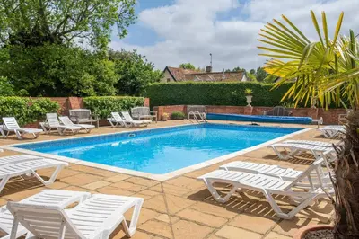 a swimming pool with white lounge chairs next to it at East Green Farm Cottages - The Hayloft in Saxmundham