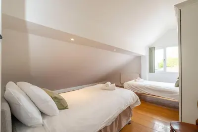 a white room with two beds and a mirror at East Green Farm Cottages - The Hayloft in Saxmundham