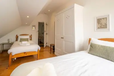 a bedroom with two beds and a staircase at East Green Farm Cottages - The Hayloft in Saxmundham