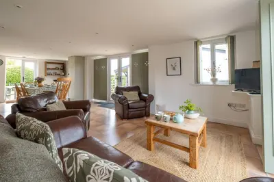 a living room with couches and a table at East Green Farm Cottages - The Hayloft in Saxmundham
