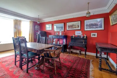 a dining room with red walls and a wooden table and chairs at Beach House - Aldeburgh Coastal Cottages in Aldeburgh