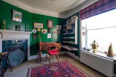 a green room with a desk and a fireplace at Beach House - Aldeburgh Coastal Cottages in Aldeburgh