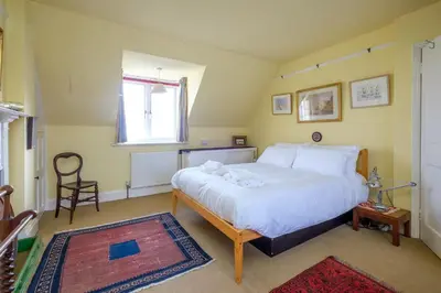 a bedroom with a large white bed and a chair at Beach House - Aldeburgh Coastal Cottages in Aldeburgh
