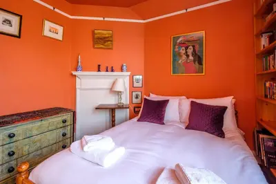 a bedroom with a large bed in an orange wall at Beach House - Aldeburgh Coastal Cottages in Aldeburgh