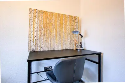 a desk with a lamp and a chair next to a wall at Free Parking Business Stay Office Fast WiFi in Colchester