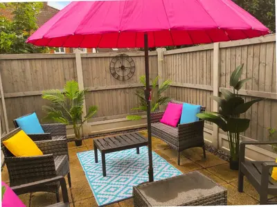 a pink umbrella on a patio with chairs and a table at Free Parking Business Stay Office Fast WiFi in Colchester