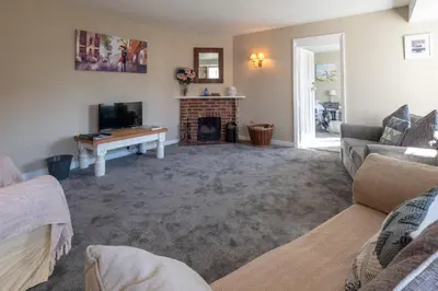 a living room with a fireplace and a tv at 6 Lakeside Avenue in Thorpeness