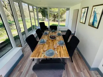 a dining room with a wooden table and chairs at Warren Lodge in Little Baddow